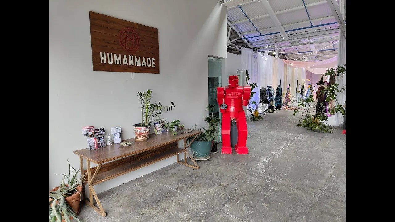 Jasne wnętrze makerspace'u z czerwoną figurą robota i roślinami